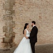Bride with groom wearing glamorous ballgown wedding dress with deep V-neck.