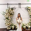 Bride Wearing Lace Fit And Flare Wedding Dress Called Fairchild By Maggie Sottero Next To The Flower Arch