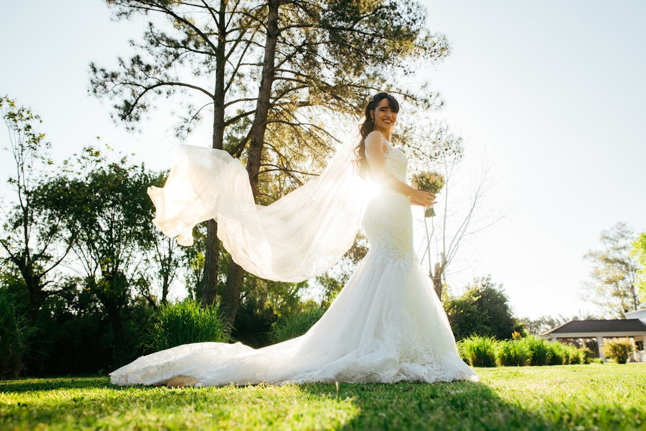 Bride With Veil Outside Holding Flower Bouquet Wearing Bridal Gown Called Giana Lynette by Maggie Sottero