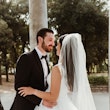 Bride with groom wearing glamorous ballgown wedding dress with deep V-neck.