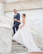 Bride wearing Marvine wedding gown by Sottero and Midgley walking up the stairs with her husband