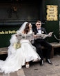 Bride wearing Saratoga by Maggie Sottero reading newspapers with her husband