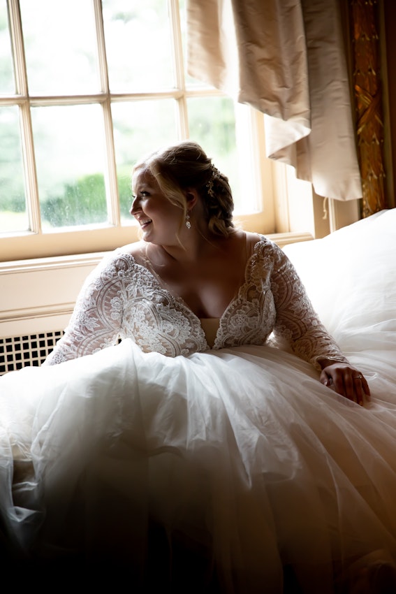 Smiling Bride Sitting in Wedding Gown Called Mallory Dawn by Maggie Sottero