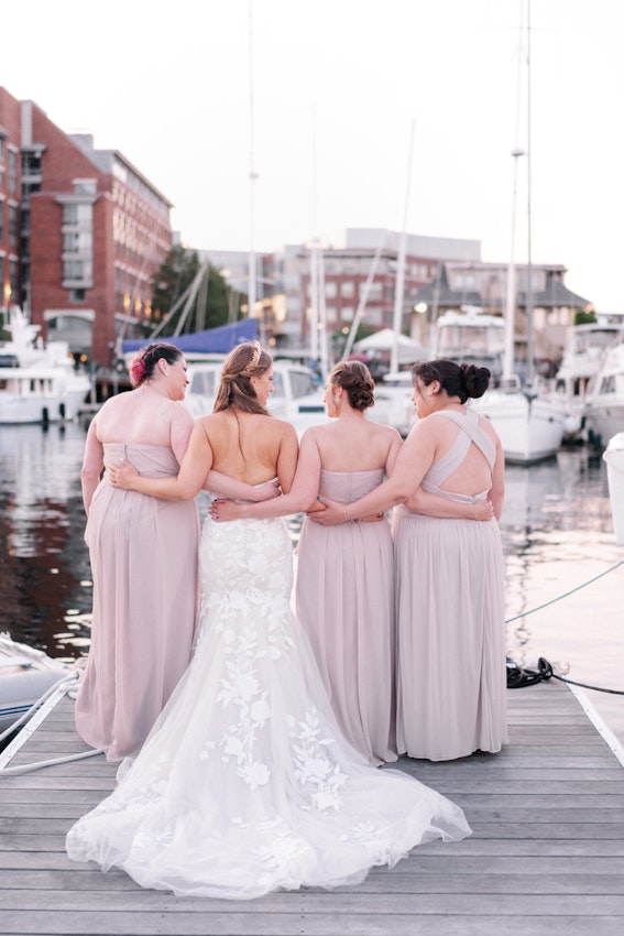 Bride with bridesmaids wearing strapless mermaid wedding dress with plunging V-neck.
