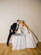 Bride wearing Zinaida by Maggie Sottero cutting the cake and kissing her husband