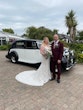 Bride wearing wedding dress called Daxton stood with groom in front of vintage car.