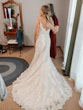 Bride posing with mother while bridesmaid takes a photo.