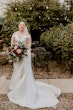 Bride Wearing Simple Fit And Flare Wedding Dress Called Josie By Rebecca Ingram In An Outdoor Patio