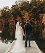 Bride Wearing Lacey Sheath Long Sleeve Wedding Dress Called Francesca By Maggie Sottero Standing With Groom On Dock Looking Over Water