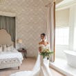Bride Wearing Simple Off-the-shoulder Wedding Dress Called Josie By Rebecca Ingram In A Lux Bathroom