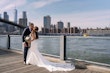 Bride Wearing Lace Crepe Bridal Dress Called Bracken By Sottero And Midgley Kissing Groom With A City Skyline Behind Them