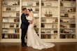 Bride wearing Kern by Maggie Sottero with her husband in front of a bookshelf