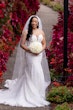 Bride Wearing Sexy Lace Wedding Dress Called Lennon By Maggie Sottero Next To Red Floral Bushes