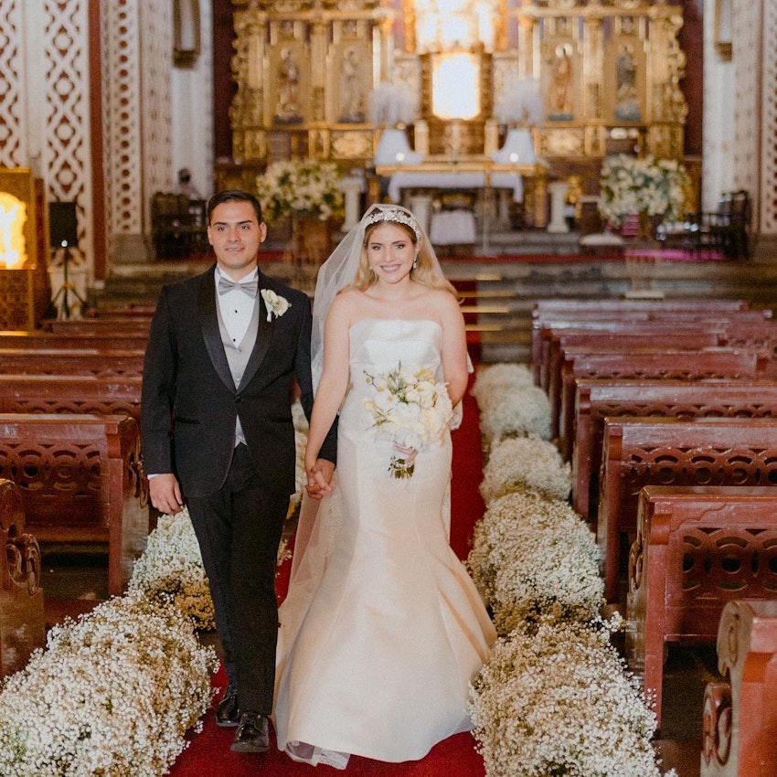 Bride Walking Down Aisle in a Church Holding Groom's Hand Wearing Bridal Dress Called Mitchell by Maggie Sottero