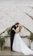 Groom Kissing Bride Wearing Plunging Lace Illusion Wedding Dress Called Raelynn By Rebecca Ingram