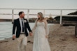 Bride Wearing Off-The-Shoulder Lace Wedding Dress Called Carson By Sottero And Midgley Walking On The Beach With Groom