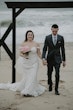 Bride wearing Frederique wedding gown by Maggie Sottero holding hands with her husband