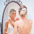 Bride touching hair looking in mirror before wedding wearing wedding dress called Inga.