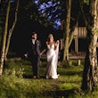 Bride and groom walking in the woods at sunset.