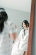 Bride looking at her wedding dress facing the mirror.