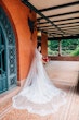 Real Bride Wearing A Fitted White Wedding Dress Named Veronique by Maggie Sottero With Long Veil And Red Roses