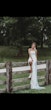 Bride Wearing Simple Fit And Flare Wedding Dress Called Francine By Rebecca Ingram Sitting On A Fence