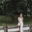 Bride Wearing Simple Fit And Flare Wedding Dress Called Francine By Rebecca Ingram Sitting On A Fence