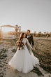 Bride And Groom Standing Together During Sunset. Bride Wearing Beautiful Boho Long Sleeve Ball Gown Called Mallory Dawn By Maggie Sottero 