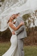 Bride with groom wearing simple sheath wedding dress with V-neck.
