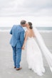 Bride Wearing Boho Sheath Wedding Dress Called Marisol By Rebecca Ingram Kissing Groom On The Beach