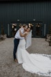 Groom With Bride In White Wedding Dress Named Sadie By Rebecca Ingram In Front Of Green Barn