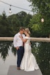 Bride wearing Josie by Rebecca Ingram cuddling with her husband on a dock