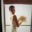 Bride holding all ivory bouquet looking over her shoulder.
