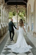 Bride wearing Cecilia by Rebecca Ingram walking down a hallway with her husband