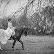 Bride wearing Drita wedding dress by Maggie Sottero riding a horse