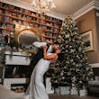 Bride Wearing Art Deco Wedding Dress Called Luella By Sottero And Midgley Kissing Groom Next To A Christmas Tree