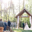 Wedding ceremony outdoors under rustic wooden hut.