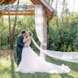 Newlyweds kissing as bride's veil floats in the breeze.