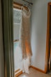 lace wedding dress called Drew hanging by the window.