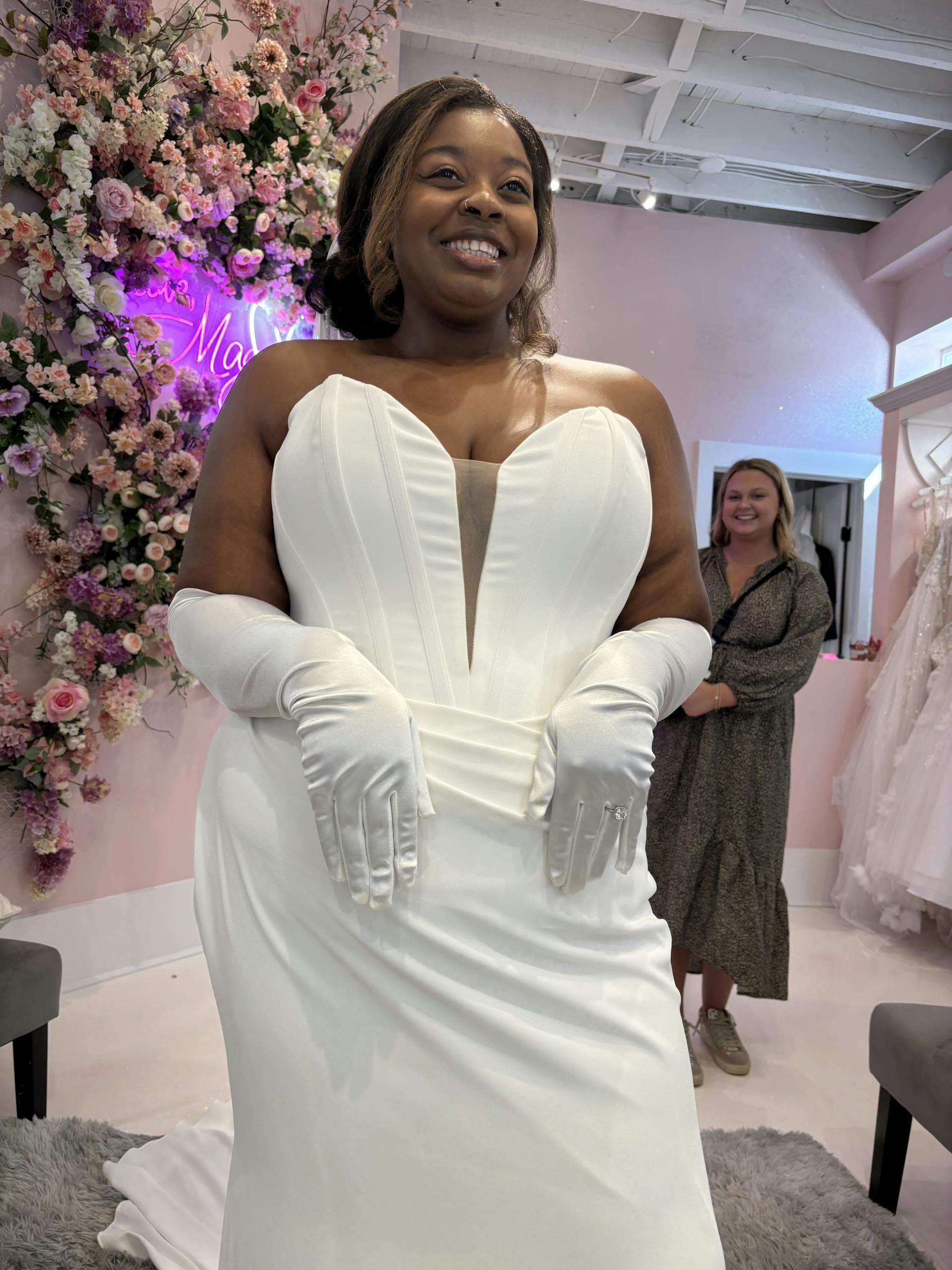 Bride Wearing Deep V-Neck Wedding Dress Called Jace By Maggie Sottero Trying On In A Boutique