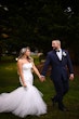 Bride wearing Holden wedding dress by Sottero and Midgley holding hands with her husband