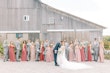 Wedding party in salmon and grey colors cheer as groom kisses his bride.