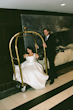 Bride Wearing Simple Aline Wedding Dress Called Selena By Maggie Sottero Riding On A Luggage Cart With Groom Pushing Her