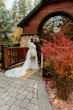 Bride Wearing Lace Wedding Dress Called Ladonna By Maggie Sottero Kissing Groom In Front Of A Cabin