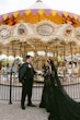 Bride Wearing Black Lace Wedding Dress Called Zander Lane By Sottero And Midgley With Groom Standing In Front Of A Moving Carousel