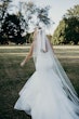 Bride walking away wearing large ivory bow in her hair.