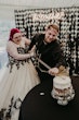 Bride Wearing Gothic Black Lace Wedding Dress Called Tristyn By Maggie Sottero With Groom Cutting The Cake With A Sword