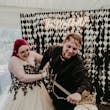 Bride Wearing Gothic Black Lace Wedding Dress Called Tristyn By Maggie Sottero With Groom Cutting The Cake With A Sword