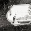 Bride and groom kissing in reflection of wedding sign.