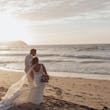 Bride wearing Johanna Lane by Maggie Sottero cuddling with her husband on the beach